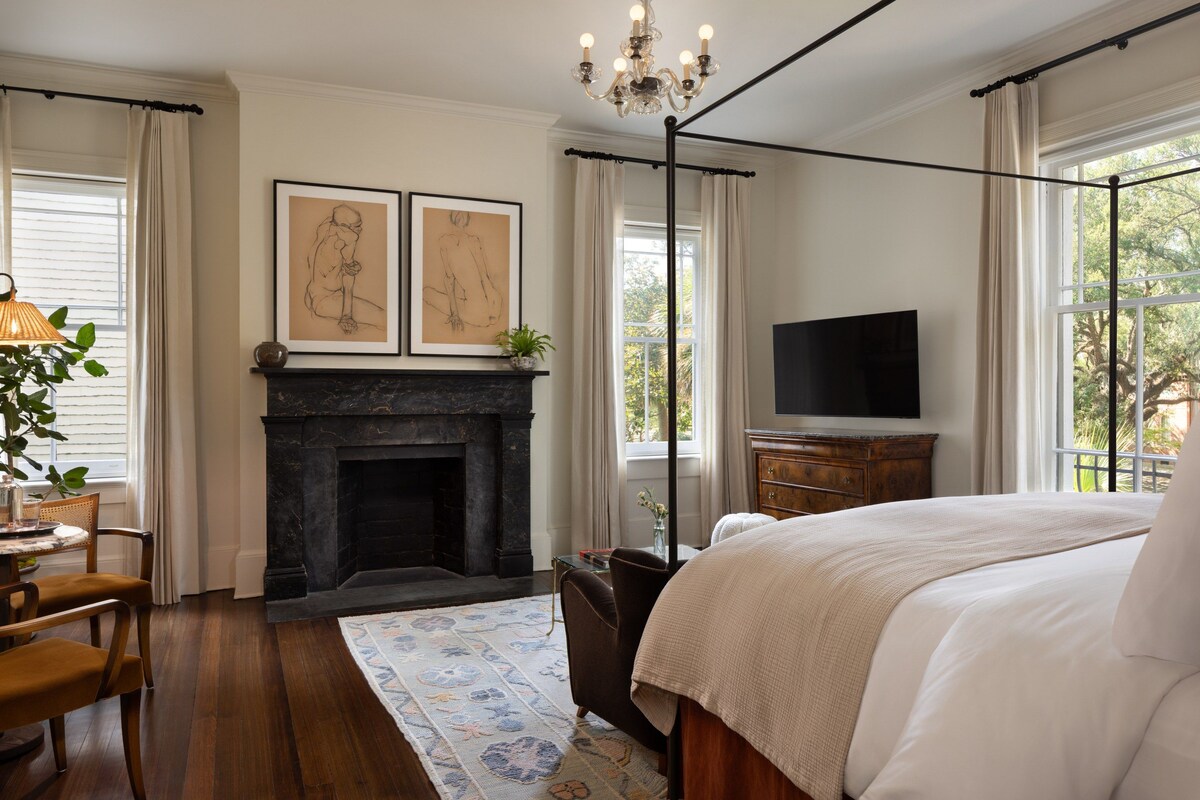 Un dormitorio con chimenea, cama, televisor y obras de arte en la pared.