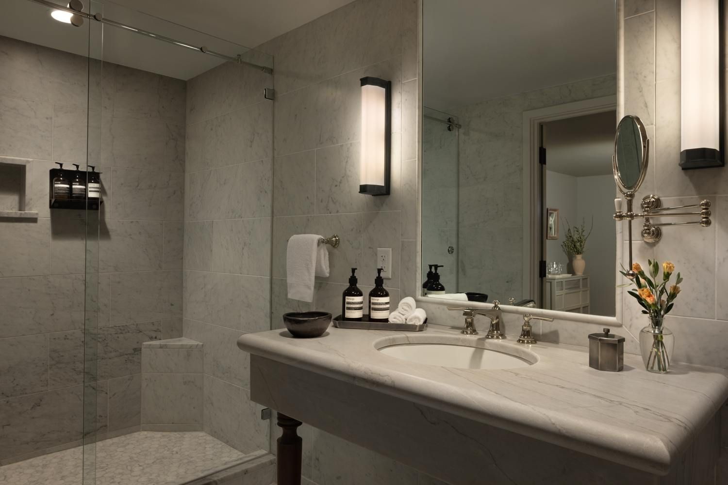 A modern bathroom with a large mirror, two sinks, and a shower area.