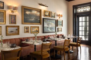 Un restaurant doté d’une longue table à manger, de sièges confortables et d’œuvres d’art accrochées aux murs, conçu pour accueillir de nombreux convives.