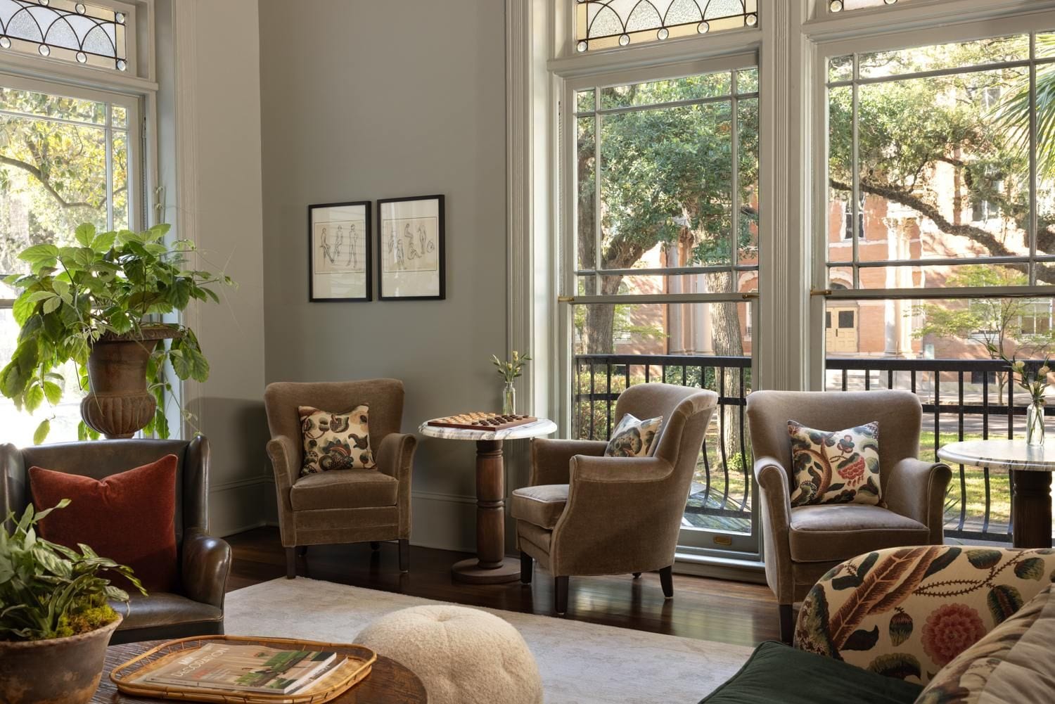 A cozy living room with large windows, comfortable seating, and a chessboard.