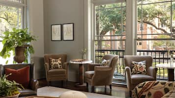 A cozy living room with large windows, comfortable seating, and a chessboard.