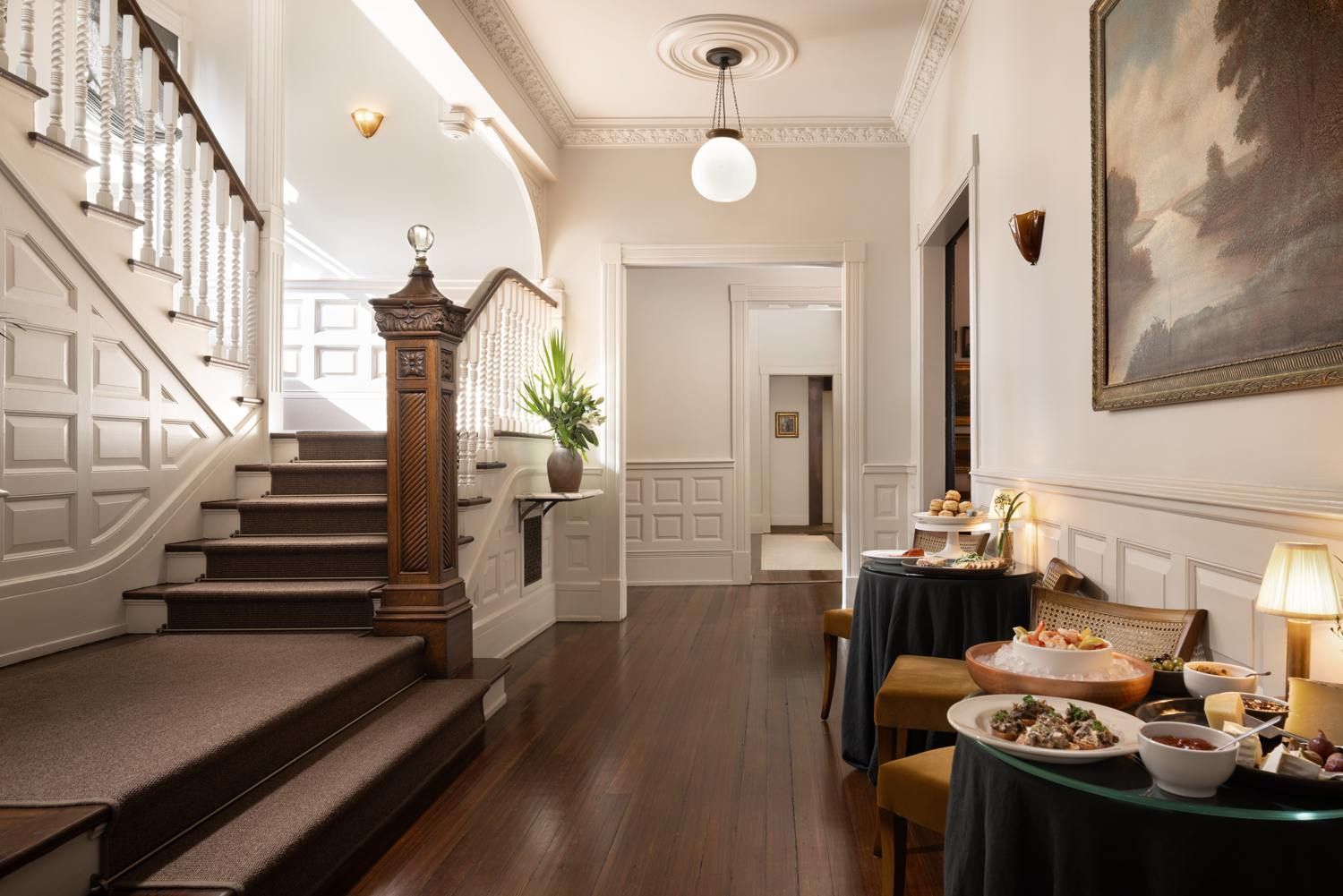 A grand staircase with a wooden handrail and a potted plant at the top.