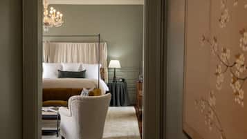 A bedroom with a four-poster bed, a side table with a lamp, and a chair.