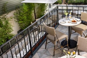 Une terrasse avec une table ronde, des chaises et une rambarde.