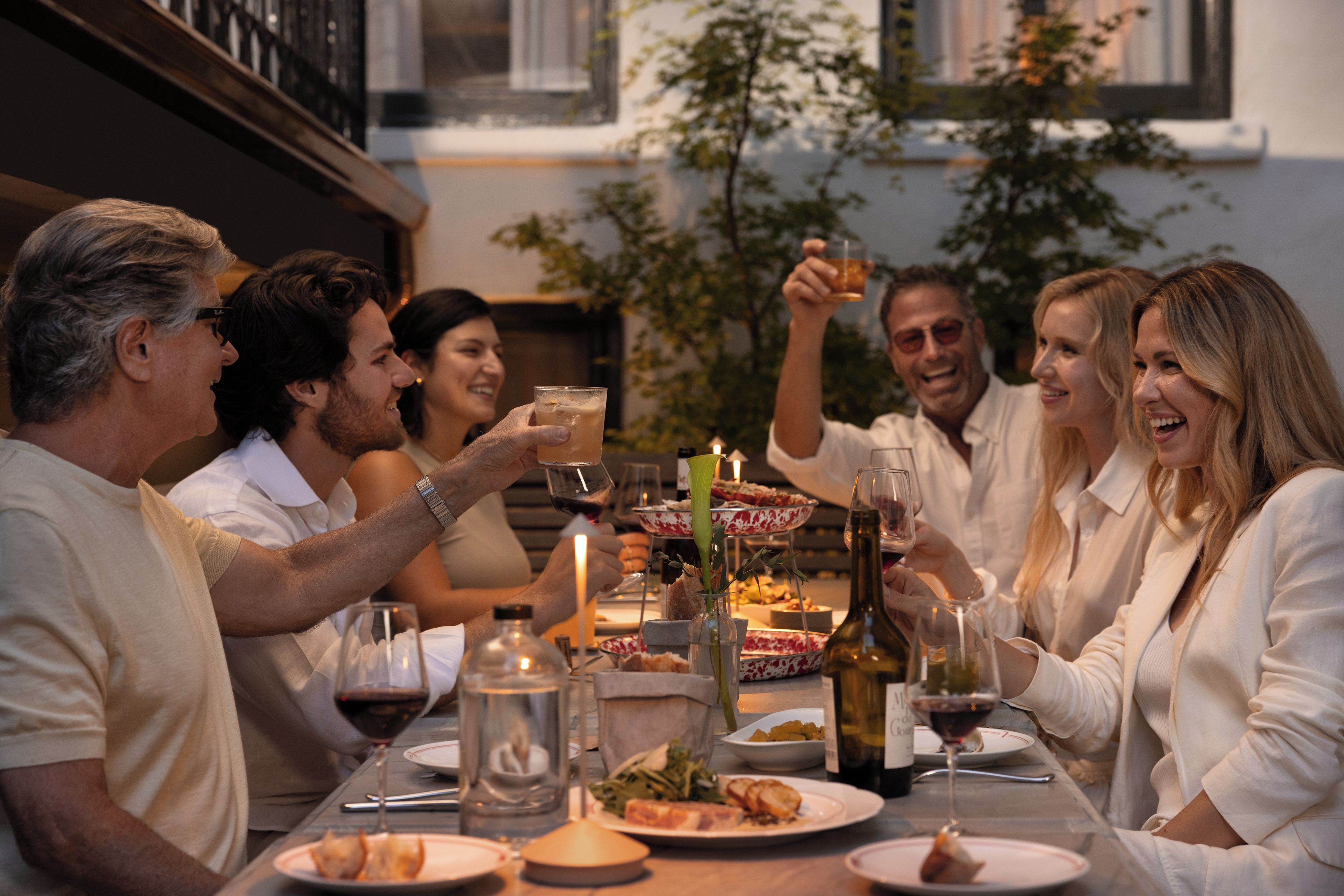A group of people seated around a table with food and drinks, suggesting a social gathering or meal.