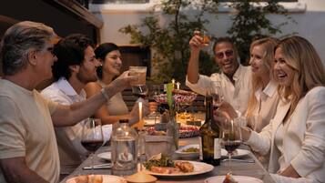 A group of people seated around a table with food and drinks, suggesting a social gathering or meal.