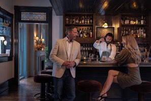 A bar area with stools, a counter, and shelves stocked with bottles.