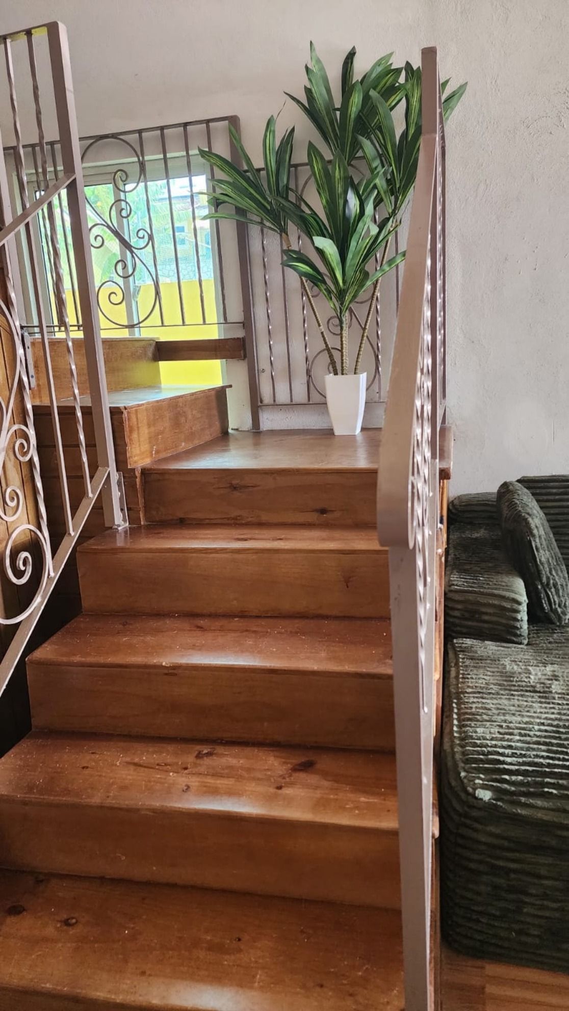 Un escalier en bois avec des rampes en métal menant à un palier.