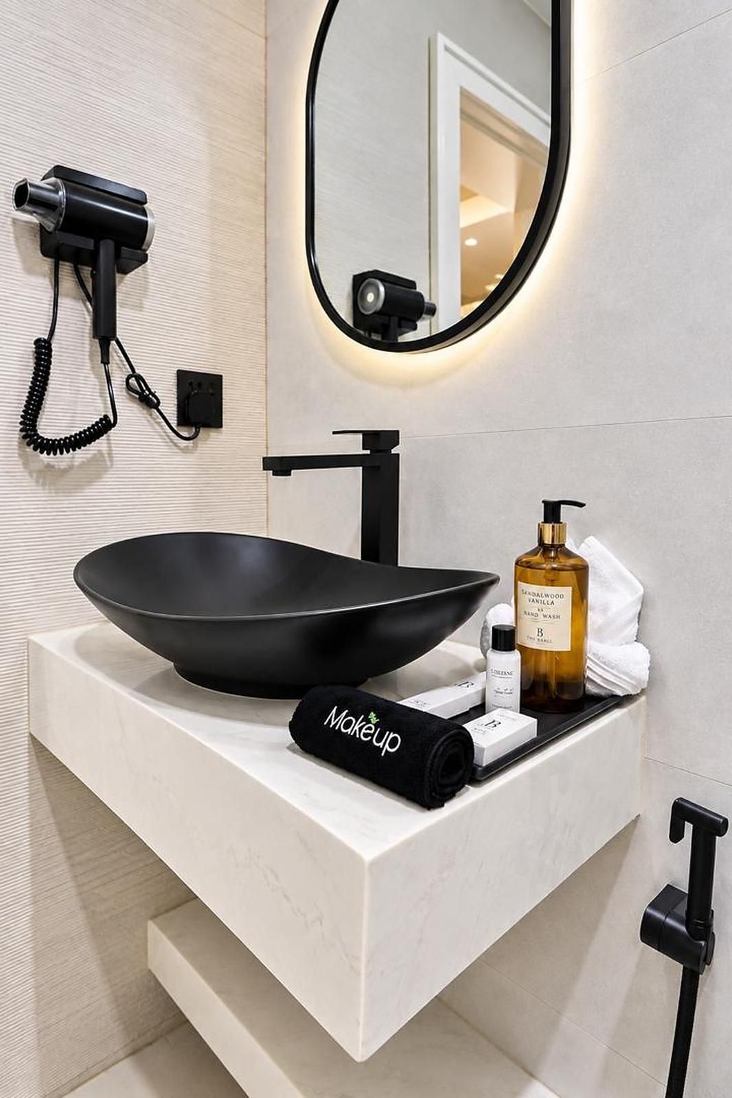 Une salle de bain moderne avec un grand lavabo noir, une serviette et des articles de toilette posés sur le comptoir.