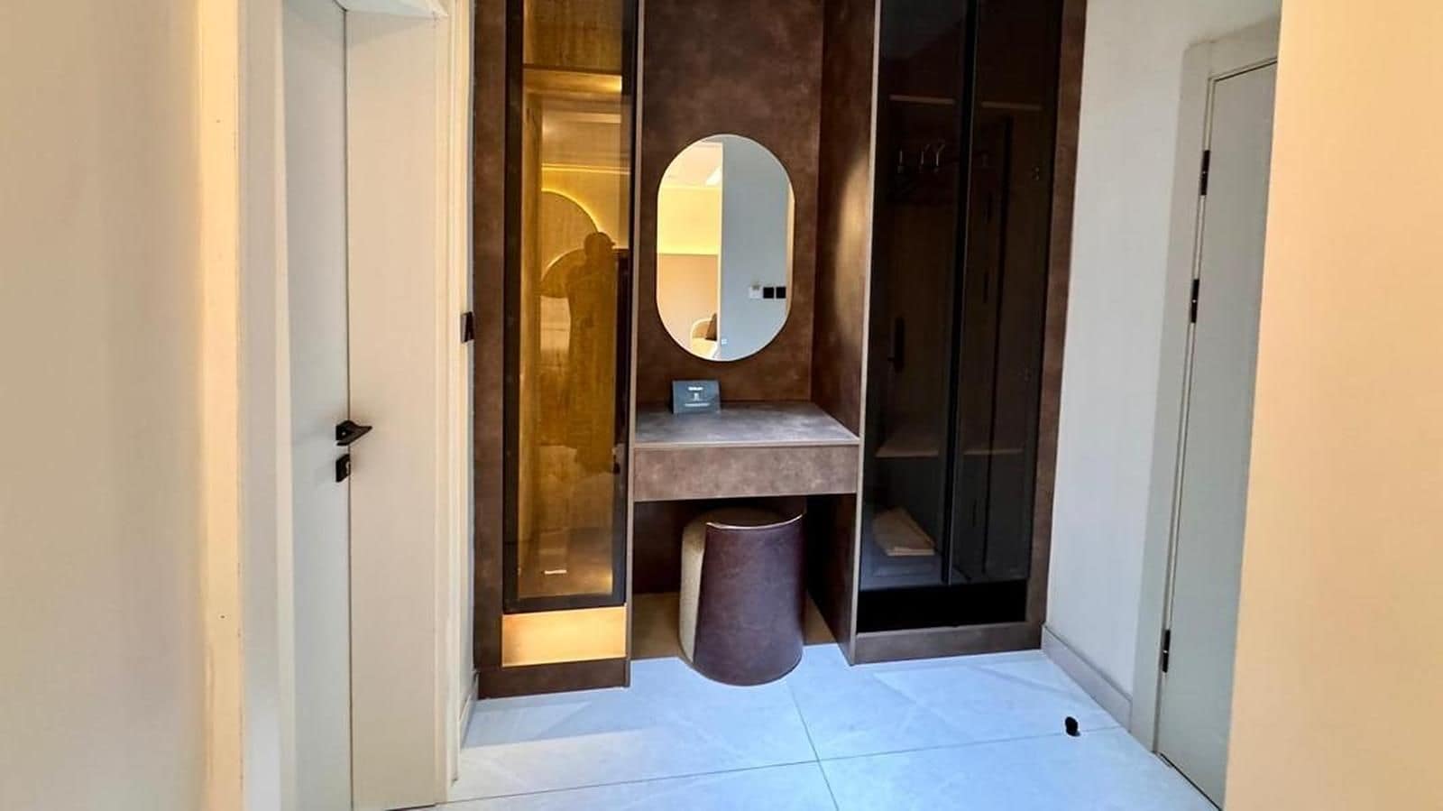 Un baño moderno con puerta de vidrio, un espejo, un lavabo y un cubo de basura.