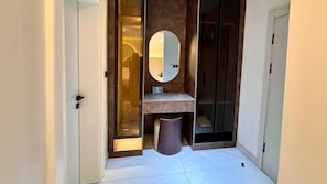 A modern bathroom with a glass door, a mirror, a sink, and a trash bin. - The Barli Hotel and Apartments (Abuja)