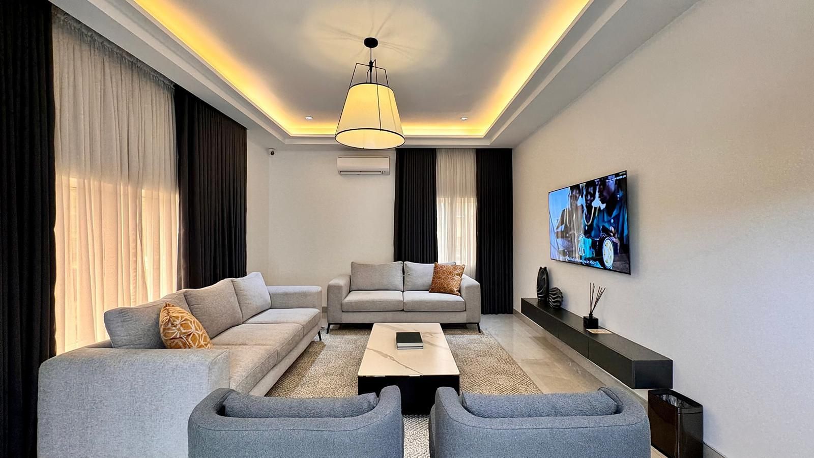 Un salon moderne comprenant un ensemble de canapés, une table basse et un téléviseur fixé au mur.
