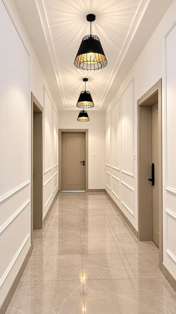 A hallway with three pendant lights, a door at the end, and a tiled floor. - The Barli Hotel and Apartments (Abuja)
