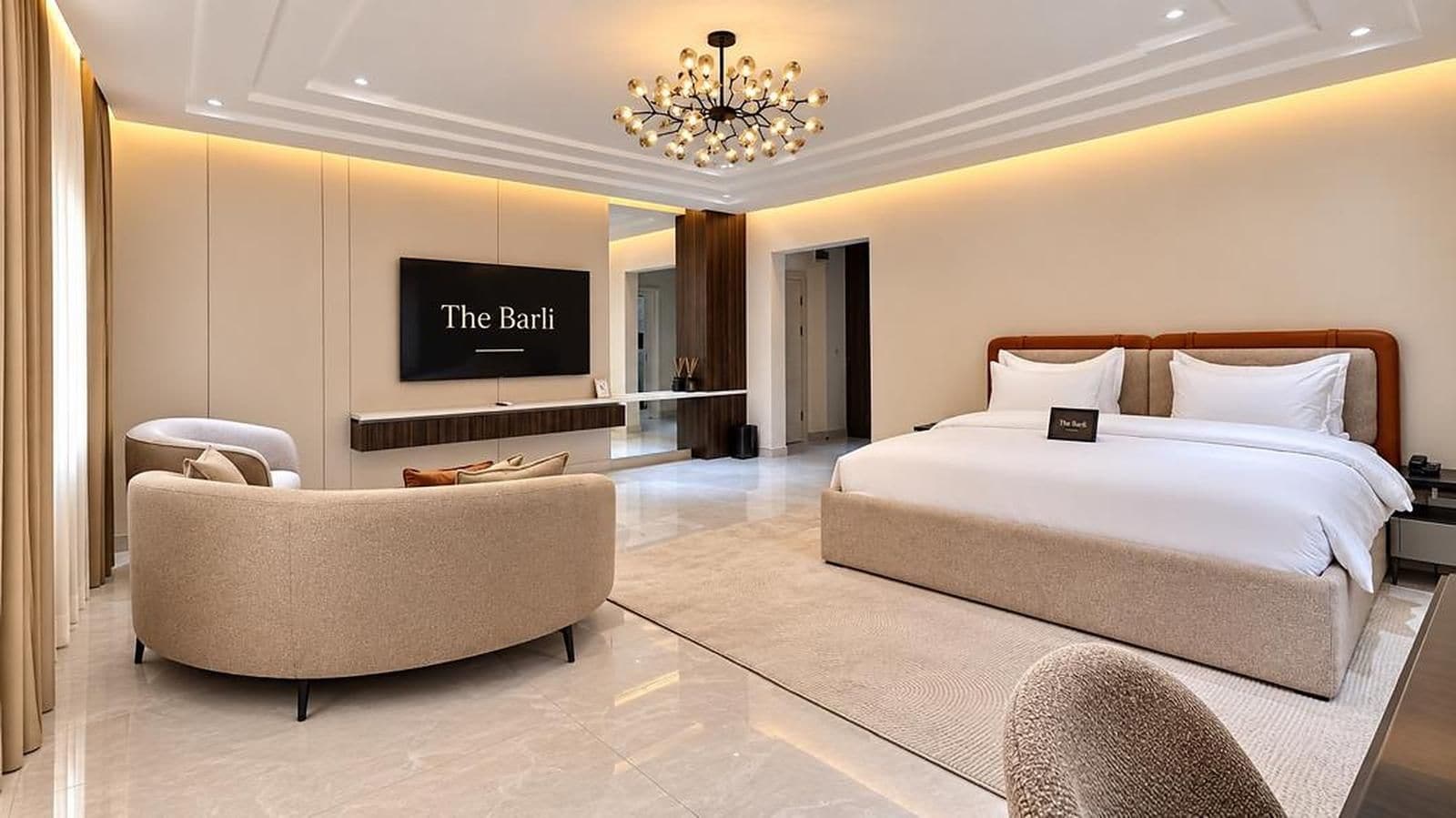Une chambre d’hôtel moderne avec un grand lit, un canapé, une télévision et un lustre.