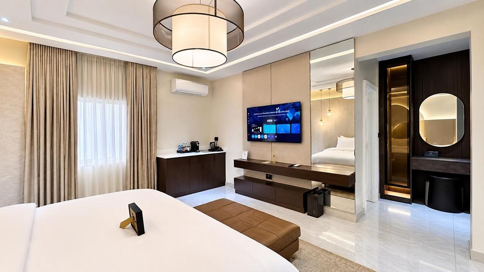 Een moderne hotelkamer met een groot bed, een bureau, een flatscreen televisie en een inloopkast.