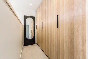Un couloir avec une armoire en bois, un sol recouvert d’une moquette et une porte dotée d’un miroir.