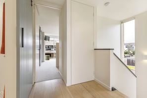 Um corredor com piso coberto de carpete, uma porta que dá para uma cozinha e uma janela com vista para o exterior.