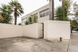A modern building with a white facade, a gated entrance, and a concrete ground. - Bayside Grove The Heart of St Kildas Coastal Life (Saint Kilda)