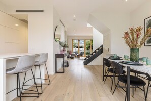 Eine moderne Küche mit Essbereich, ausgestattet mit einer Treppe, einem großen Spiegel und Blick ins Freie.
