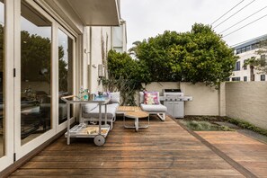 Eine Terrasse mit Grill, Gartenmöbeln und Blick auf eine Stadtlandschaft.