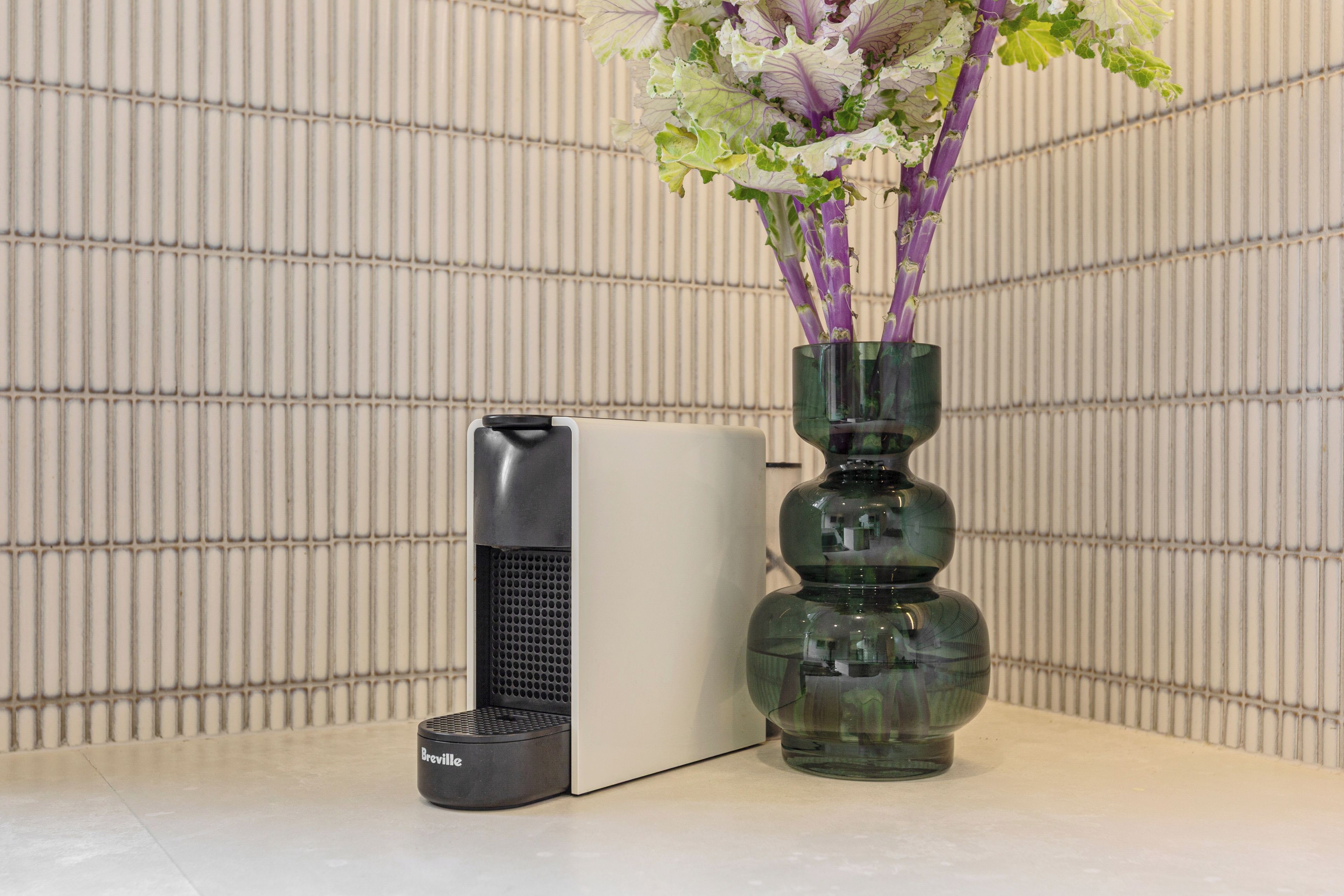 A Breville appliance next to a vase with flowers.