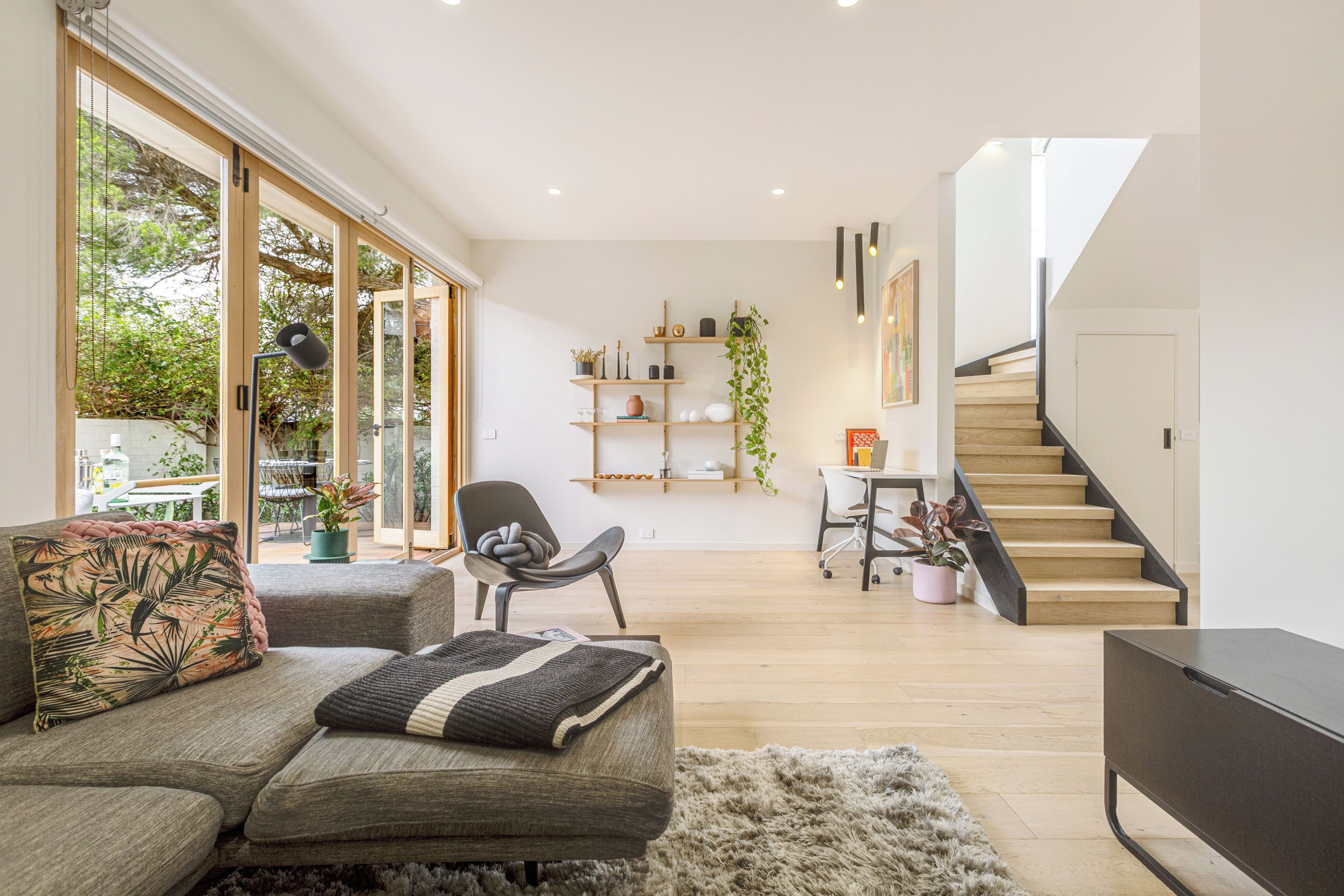 Un salon moderne comprenant un canapé, un fauteuil, une table basse et un escalier menant à un niveau supérieur.