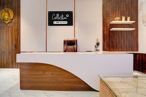 A reception desk with a wooden finish, a sign above it, and a small statue on the counter. - Collection O Narsi Vihar Park Deluxe (Mathura)