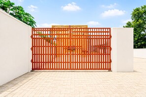 A gated entrance with a metal gate and a white wall on one side. - Collection O Narsi Vihar Park Deluxe (Mathura)