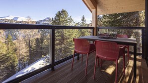 A wooden deck with a table and chairs, overlooking a snowy mountain and forest. - Superior Chalet #1 With Sauna & Hot Tub (Stadl-Predlitz)