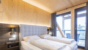 A bedroom with a large bed, a nightstand, and a window with curtains. - Superior Chalet #1 With Sauna & Hot Tub (Stadl-Predlitz)