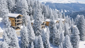 A mountain lodge with multiple wooden cabins surrounded by snow-covered trees and a mountain backdrop. - Superior Chalet #1 With Sauna & Hot Tub (Stadl-Predlitz)