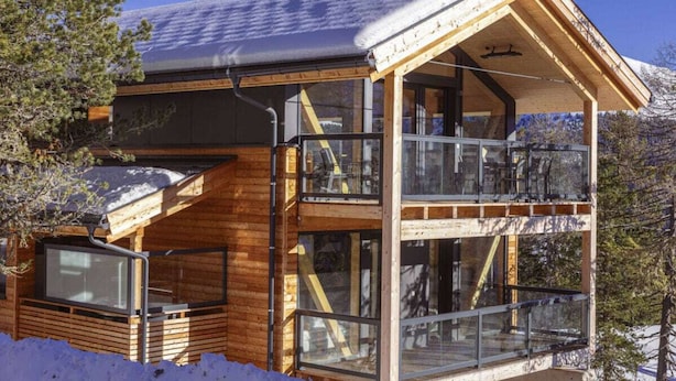 A wooden cabin with a balcony and large windows, surrounded by snow. - Superior Chalet #1 With Sauna & Hot Tub (Stadl-Predlitz)