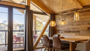 A dining area with a wooden table, chairs, and pendant lights. - Superior Chalet #1 With Sauna & Hot Tub (Stadl-Predlitz)
