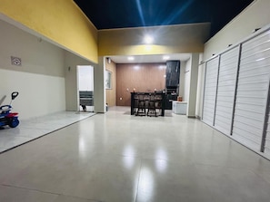 A spacious indoor area with a central table and chairs, a closed door, and a toy car on the left. - Lençóis Maranhenses House (Barreirinhas)