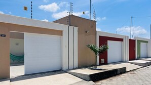 A row of buildings with closed garage doors, a small tree, and a clear sky. - Lençóis Maranhenses House (Barreirinhas)