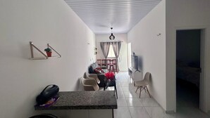 A modern living room with a dining area, a kitchen counter, and a TV. - Lençóis Maranhenses House (Barreirinhas)