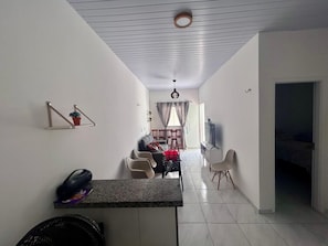 A modern living room with a dining area, a kitchen counter, and a TV. - Lençóis Maranhenses House (Barreirinhas)
