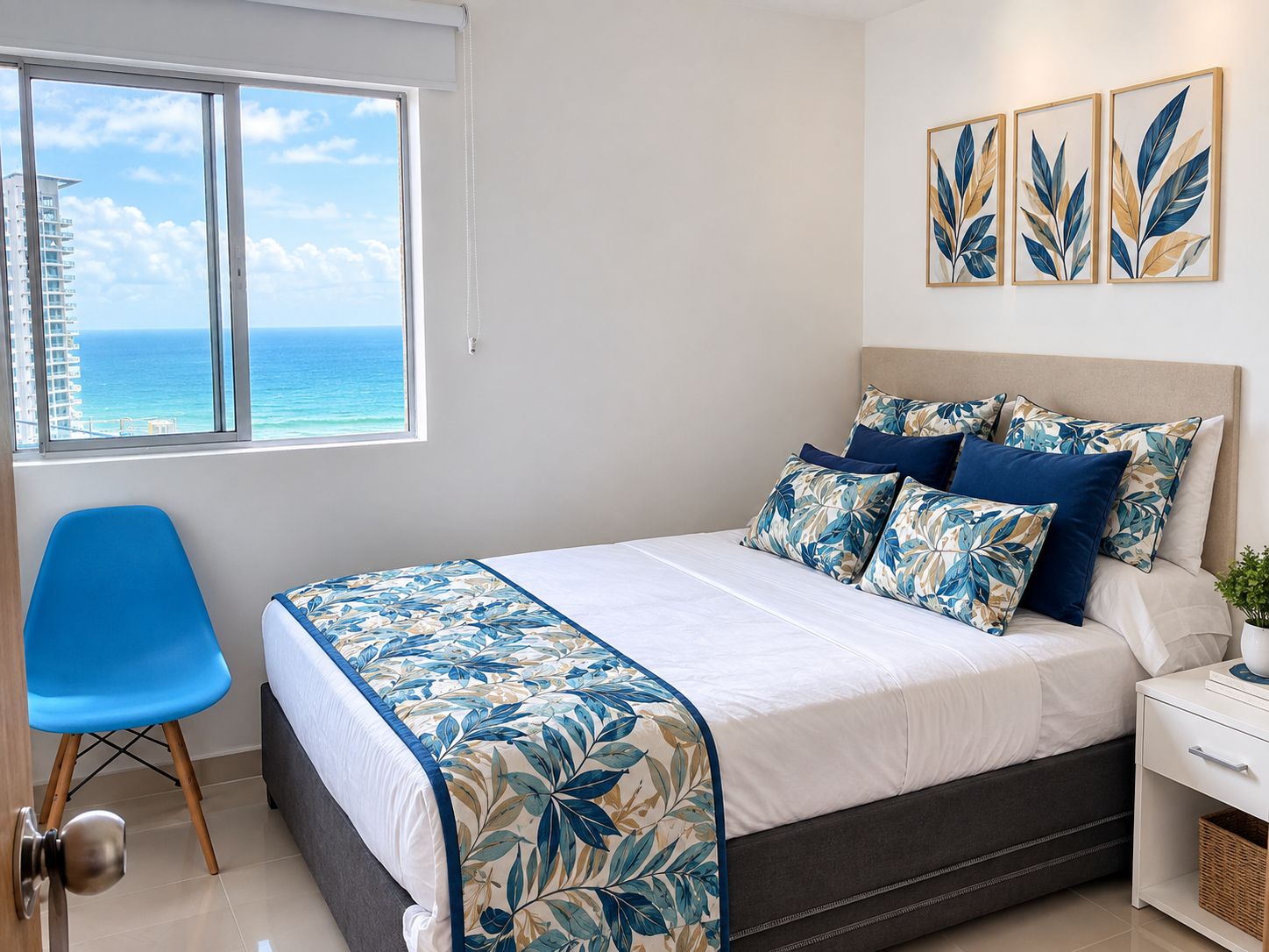 A bedroom with a bed, a chair, a nightstand, and a window with a view of the ocean.