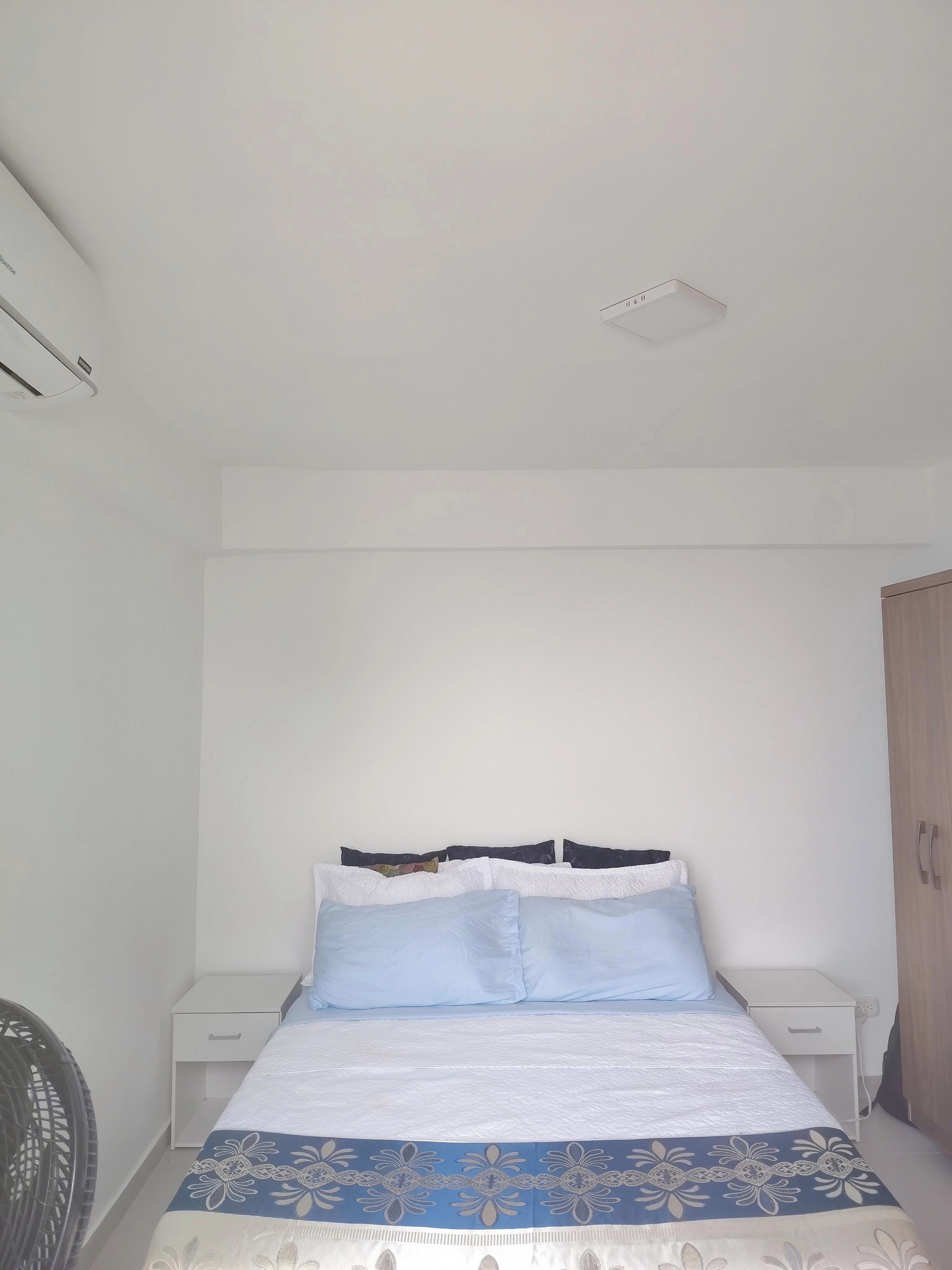 A bedroom with a bed, bedside tables, a chair, and a wardrobe.