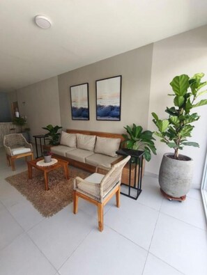 Ein Wohnzimmer mit einer Couch, zwei Sesseln, einem Couchtisch und einer großen Topfpflanze.