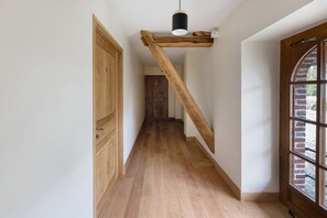 Eine Holztreppe mit einer schwarzen Leuchte, die zu einem Raum mit einem großen Bogenfenster führt.