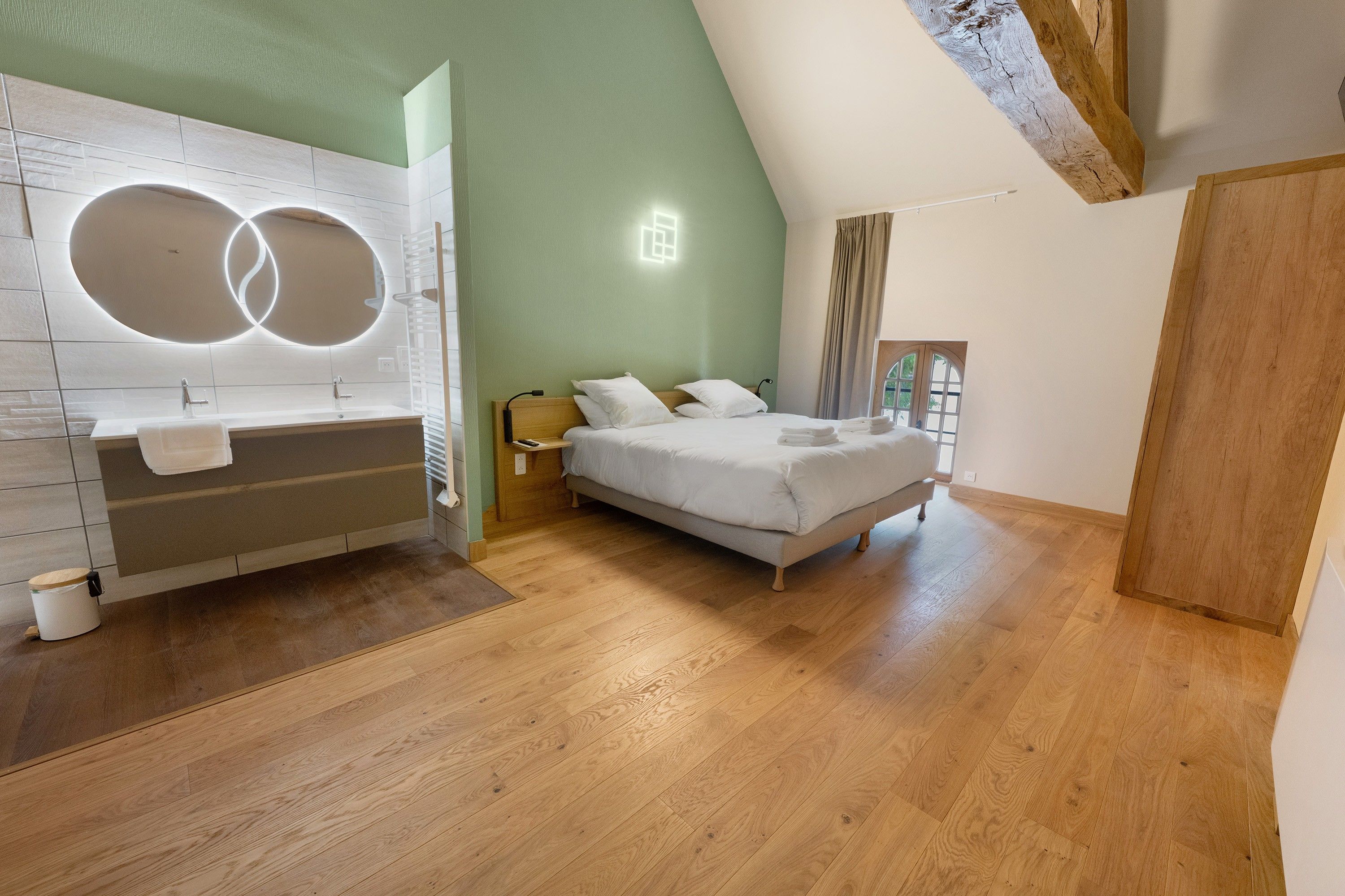 Un dormitorio moderno con una cama grande, una bañera integrada y un tragaluz.