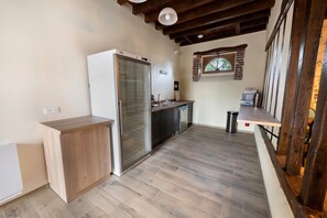Eine kleine Küche mit einem integrierten Kühlschrank, einer Holz Arbeitsplatte und einer Wand aus Ziegelsteinen.