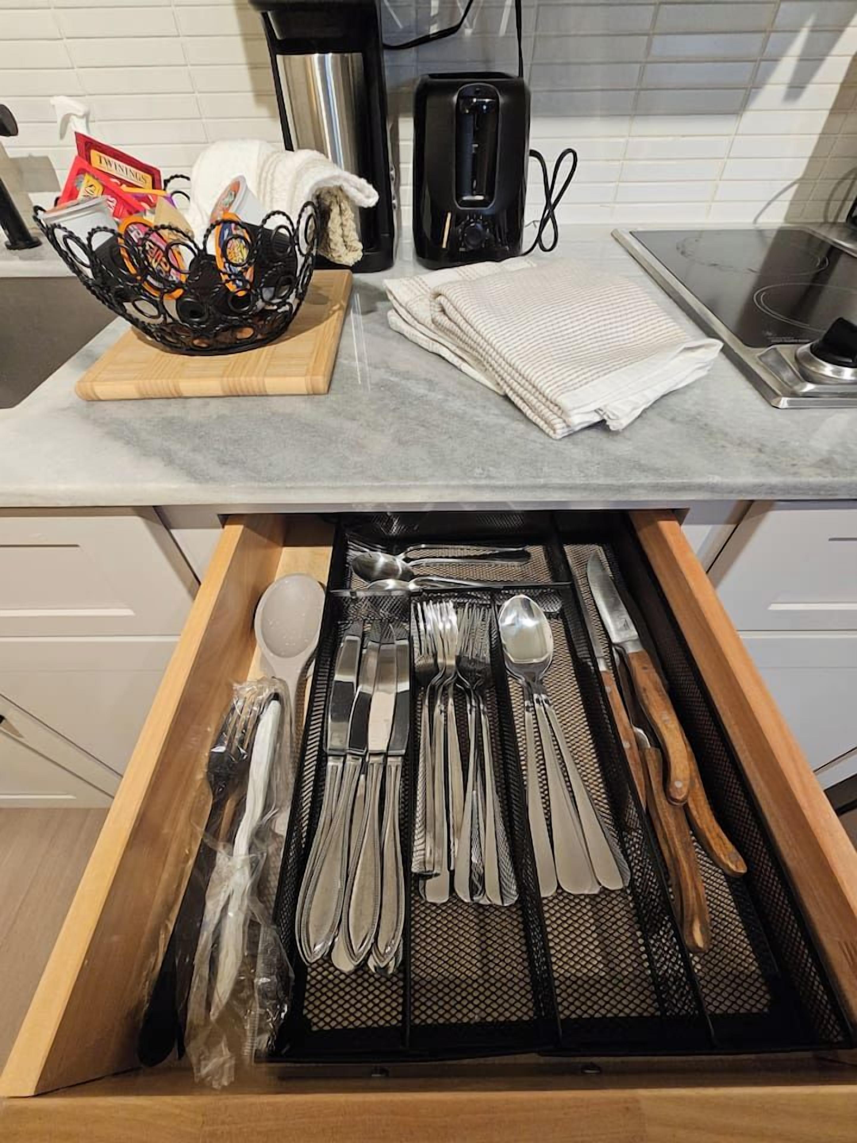 A kitchen with a coffee maker, a basket of items, and a drawer with utensils.