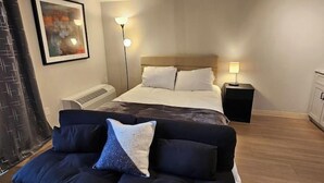 Un dormitorio moderno con cama, sofá, mesita de noche y lámpara de pared.