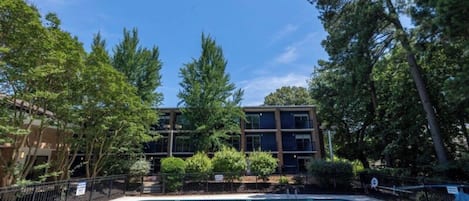 A rectangular pool with a metal ladder, surrounded by a fence and trees.