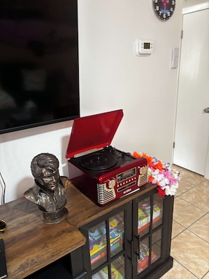 A room with a wooden table, a red vintage radio, a bust sculpture, and a Monopoly board game. - Flamingo Rock Three Minute Walk to the Gulf! (Okaloosa Island)