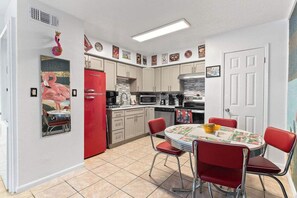 Une cuisine compacte avec un coin repas, comprenant un réfrigérateur, un four à micro-ondes, une cuisinière et une petite table avec des chaises.