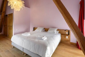 Ein Schlafzimmer mit einem großen Bett, einem Holzkopfbrett und einer schrägen Decke.