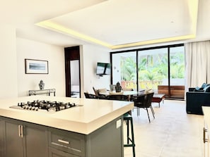 A modern kitchen with a central island, dining area with chairs, a sofa, and a TV mounted on the wall. - Two-bedroom apartment in Cruz de Huanacaxtle with beach access (Nuevo Nayarit)